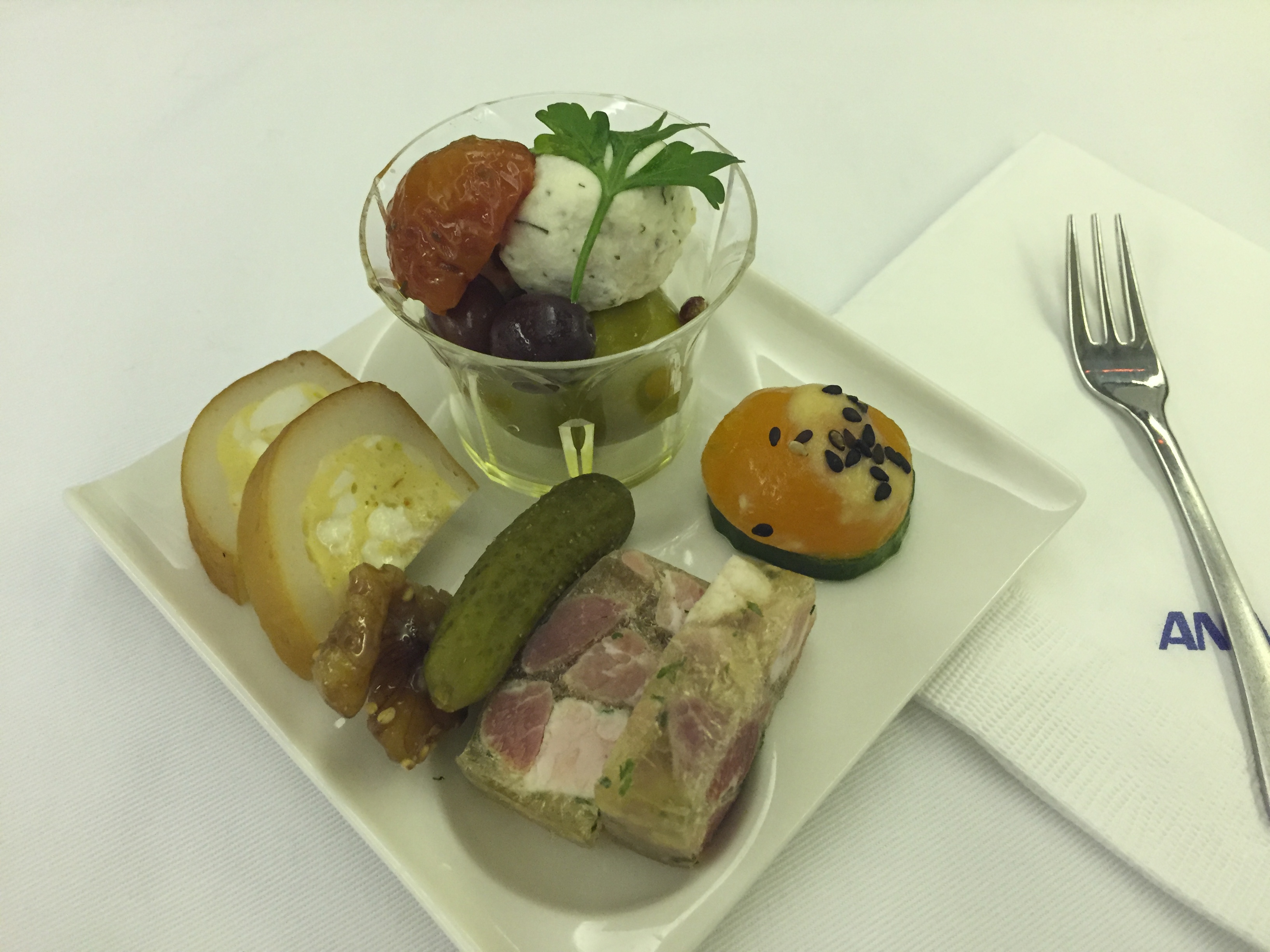 International amuse — pâté terrine with cornichon, mozzarella ball with cherry tomato, olives, sesame mochi