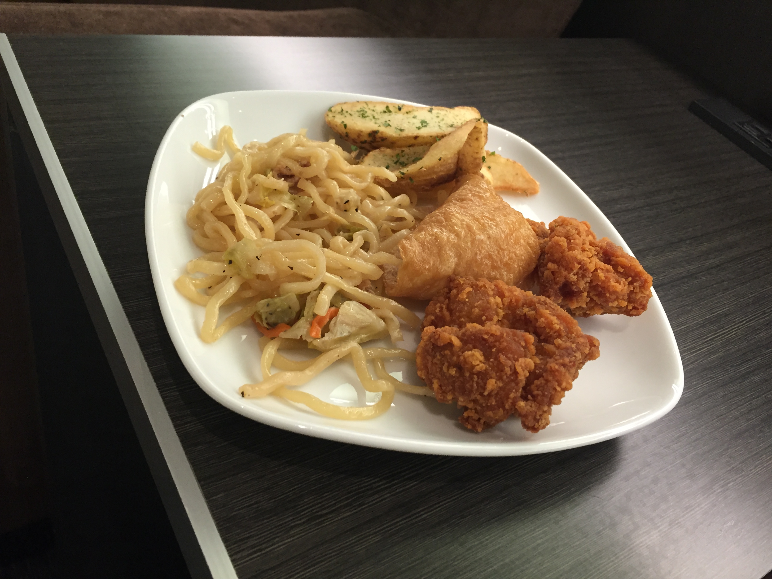 A plate of fried chicken karaage, gyoza, and stir-fried noodles from the lounge buffet