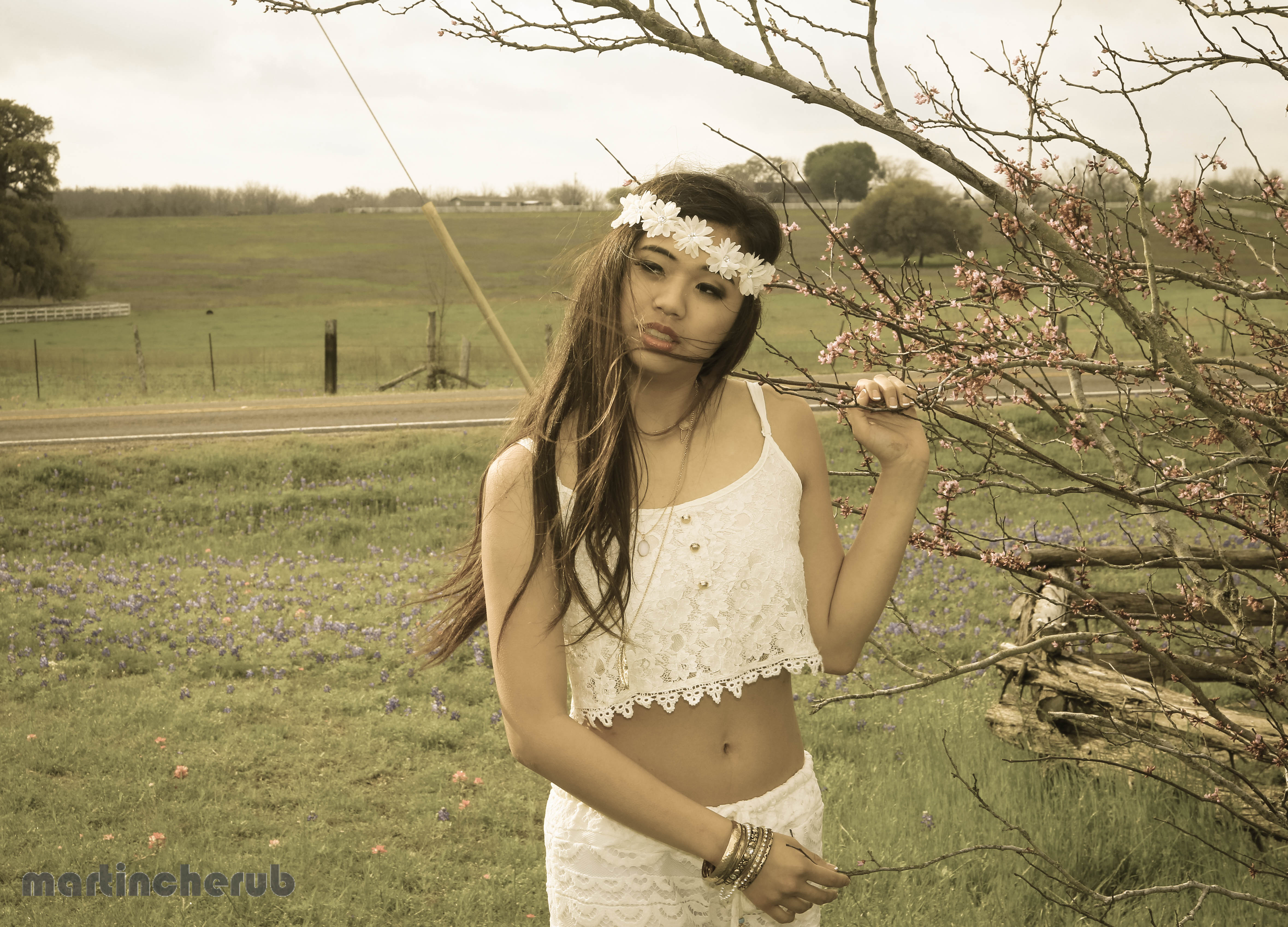 Tiffany holding a redbud branch, sepia-toned edit, bluebonnet field in background