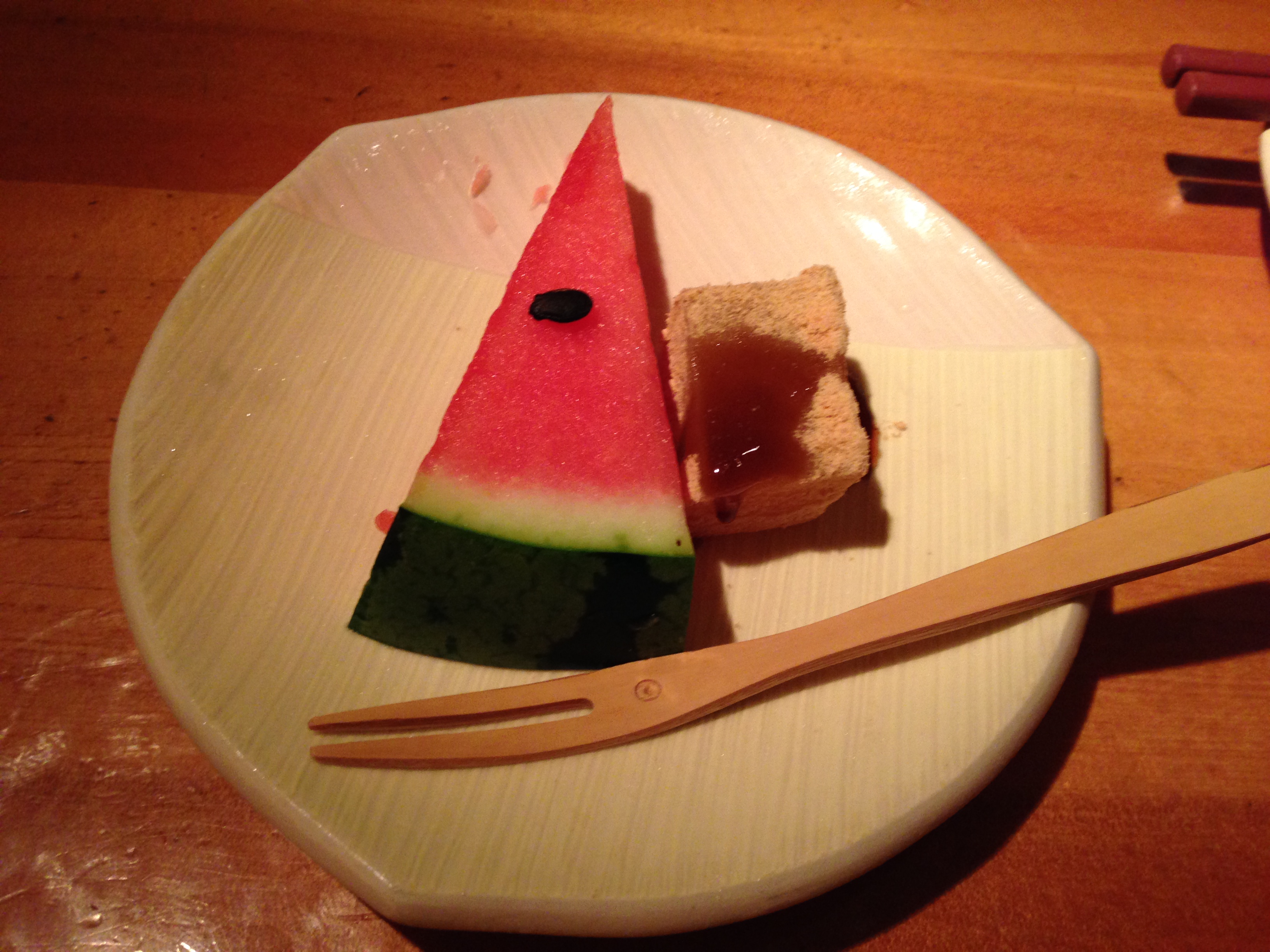 Watermelon and a small block of mochi-like sweet on a wooden board