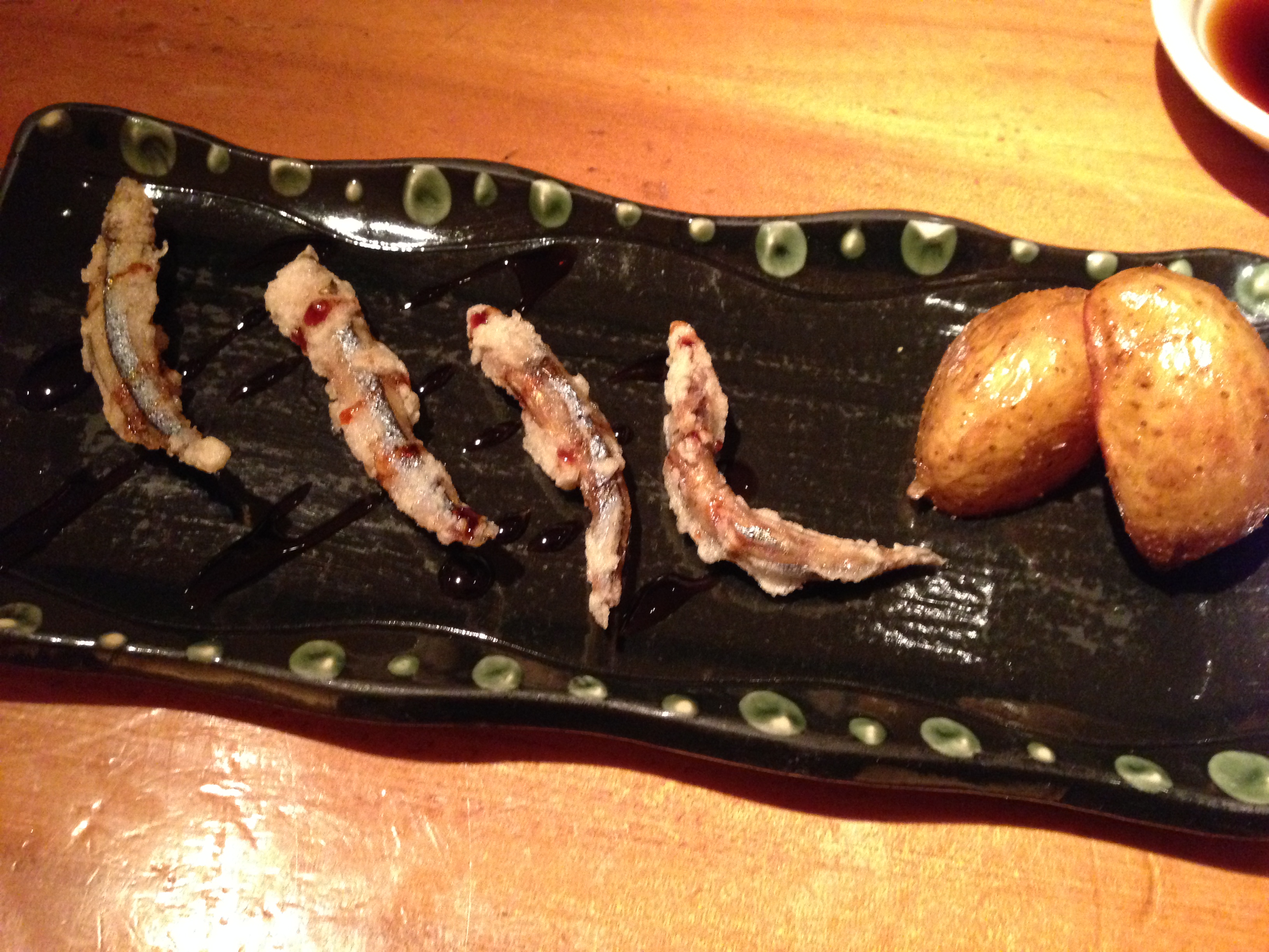 Tempura — silver-stripe round herring and edible flower buds of the fuki plant on a green-spotted plate