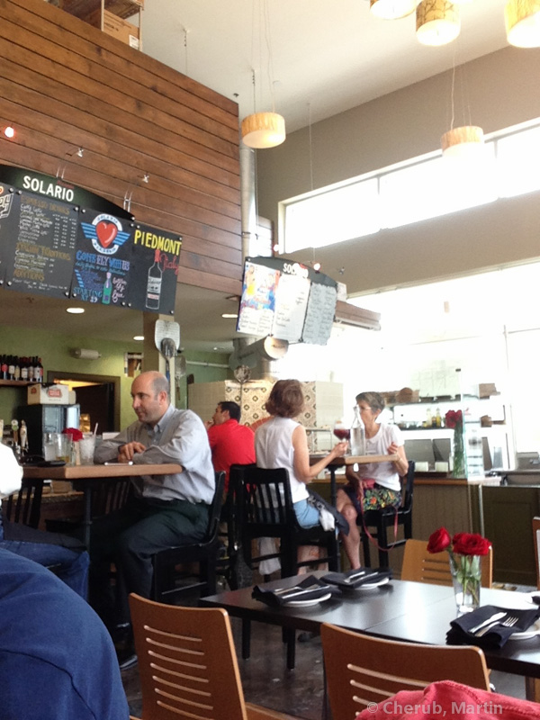 Inside Pizzeria Solario — bright, casual, with a counter and chalkboard menu