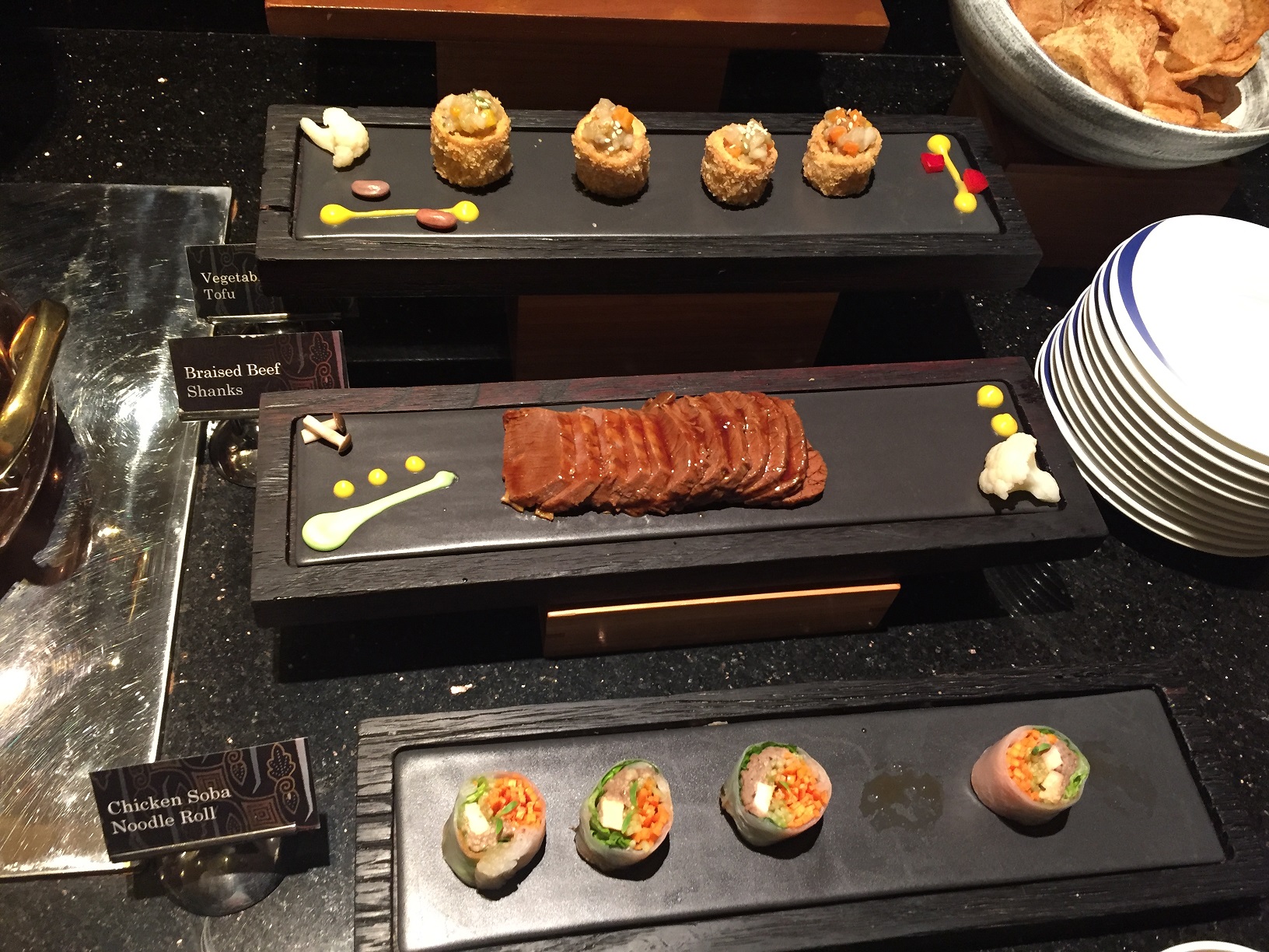 A buffet of small bowls and dishes — soups in cups, plated charcuterie, ham, smoked salmon, and small pastries