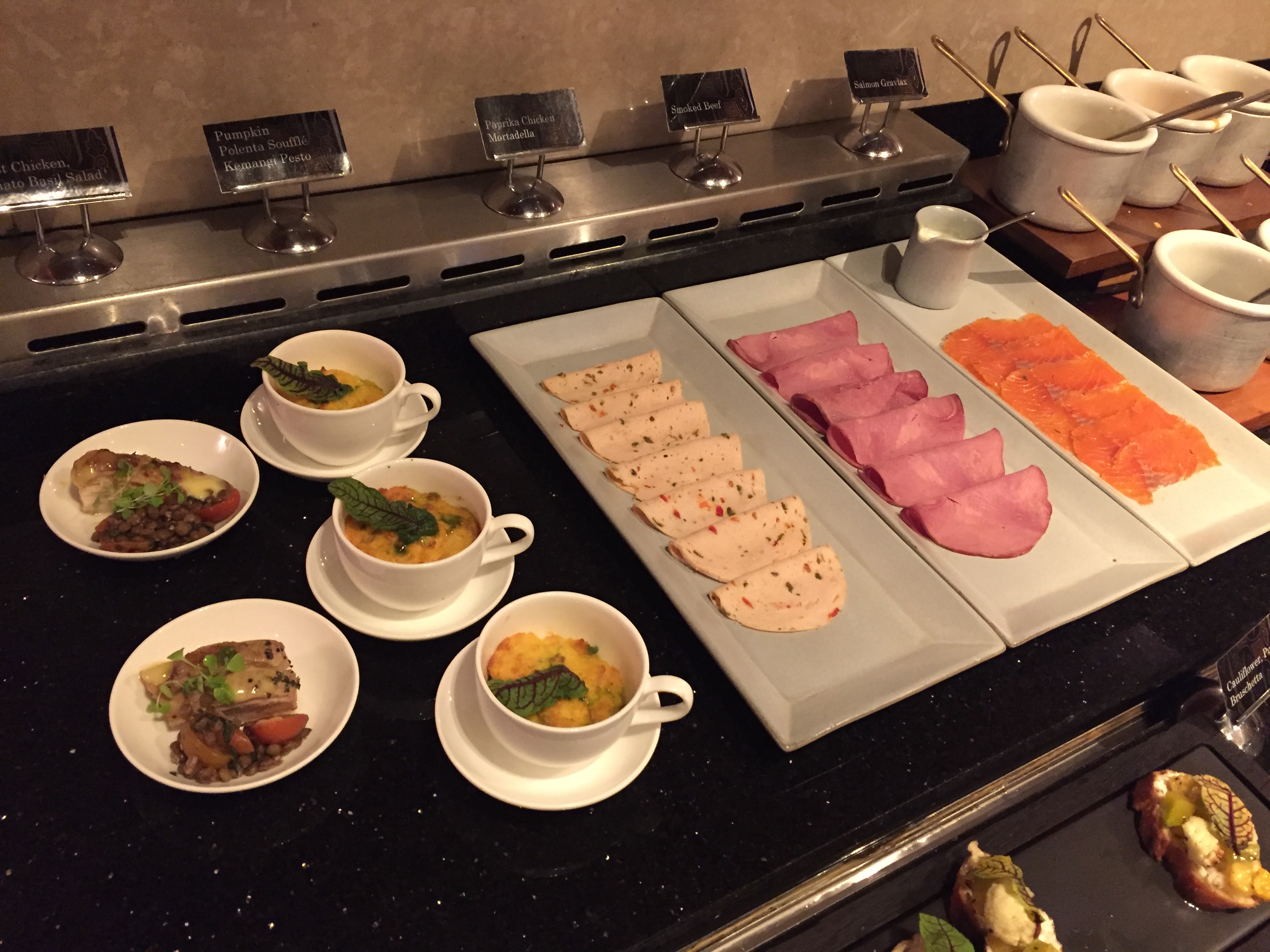 A spread of small bites — terrines, smoked beef, prawns, and assorted small dishes lined up across a black counter