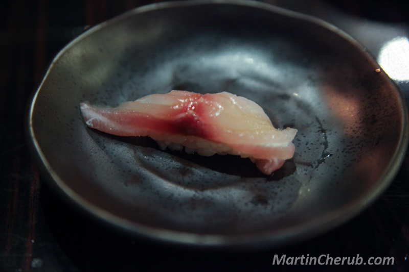 White fish nigiri on a dark plate