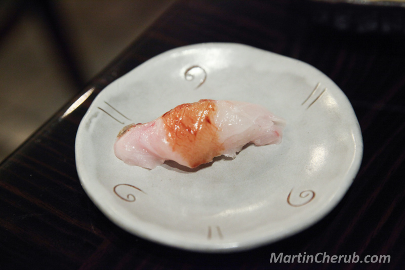 Nigiri with seared skin on a white swirl plate