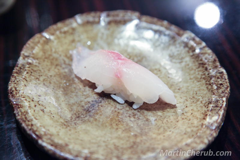 White fish nigiri on a brown ceramic plate