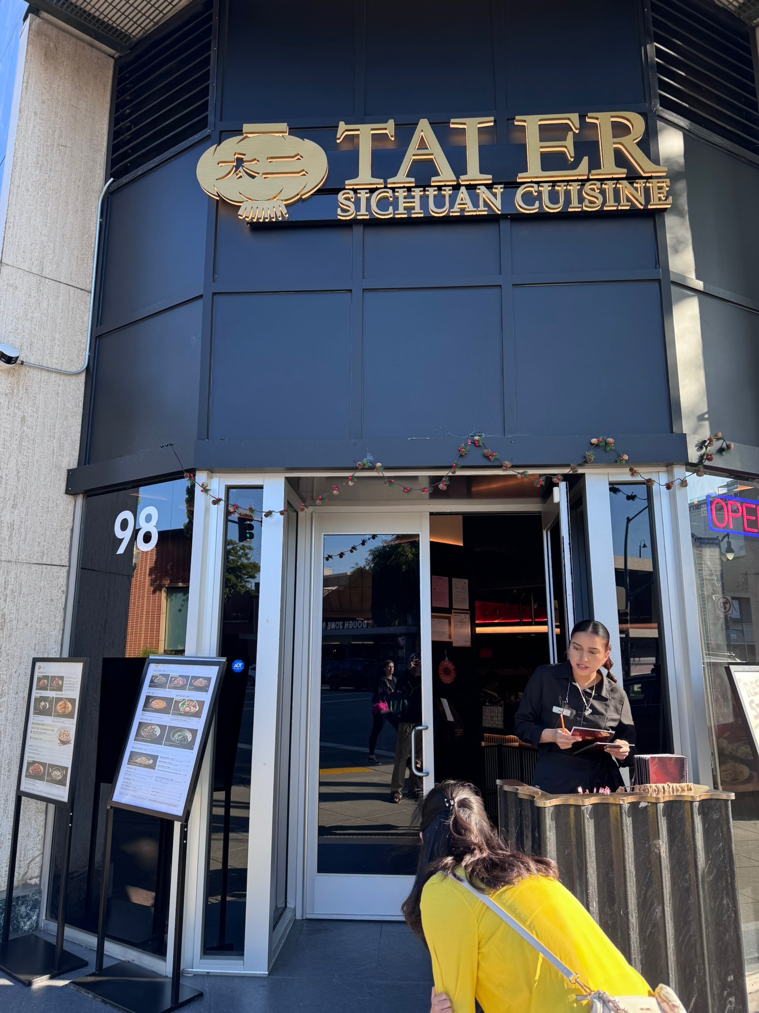 The Tai Er Sichuan Cuisine storefront in downtown San Mateo — black-and-gold signage above the entrance, a host station out front